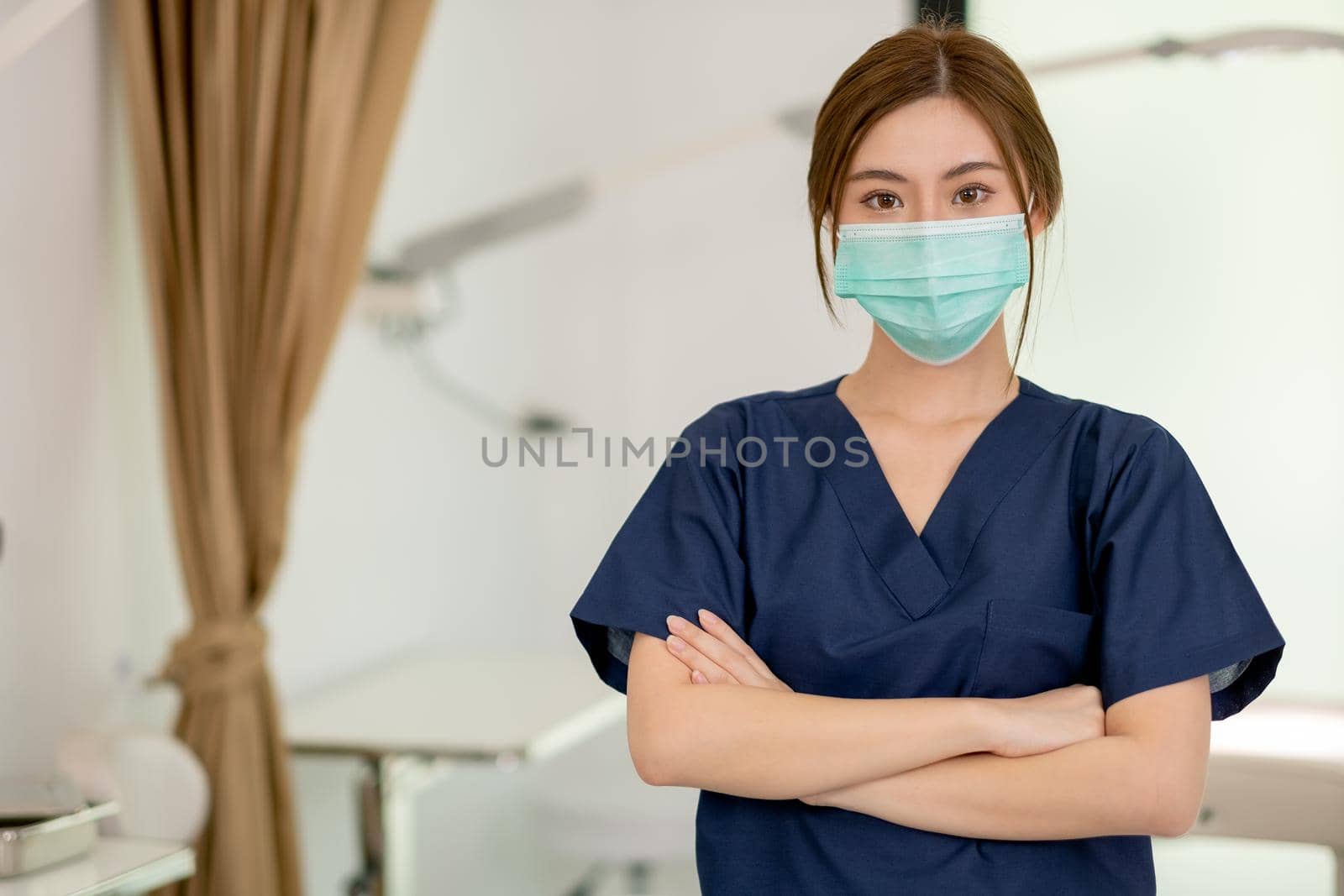 Beauty clinic worker wearing hygiene mask and stand with arm-crossed in workplace area. Beauty business for good appearance to people during covid-19 pandemic concept.