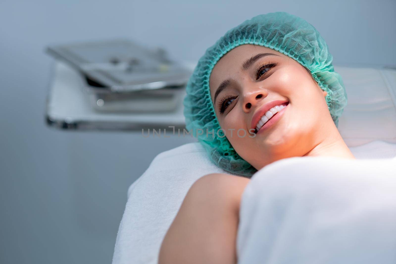 Asian young woman smile and lie on bed during preparation of beauty treatment in beauty clinic or salon.