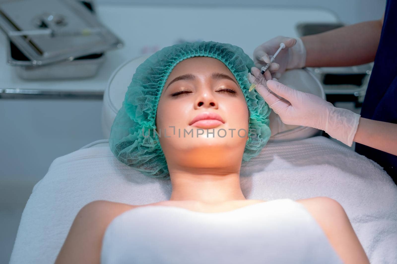 Close up hands of beauty clinic staff holds syringe with needle containing chemical for beauty treatment to Asian customer woman in clinic.