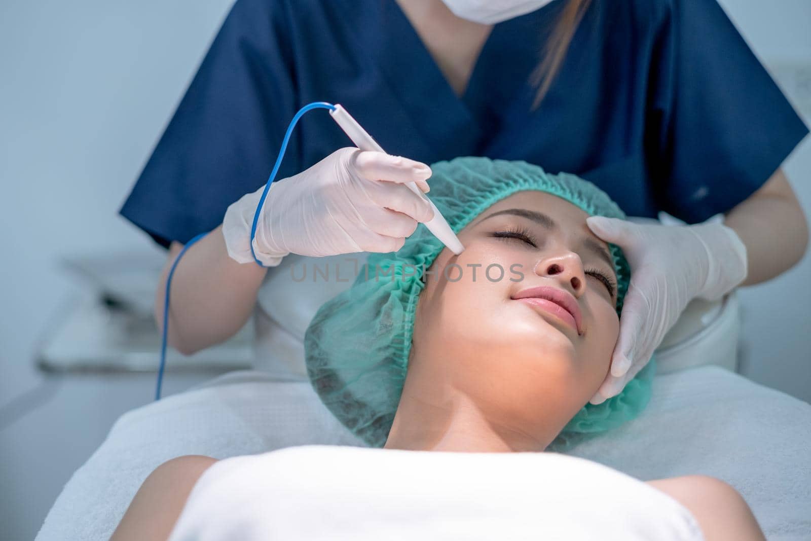 Beautiful woman is treated her face by using tools shape like pen and process by beauty staff as doctor or nurse in clinic salon. Concept of beauty clinic for beauty of body, Asian beauty.