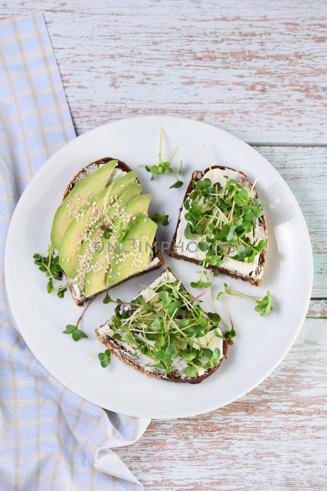 Sandwich rye bread with cereals, cream cheese, avocado and sprouted radish sprouts (microgreen)