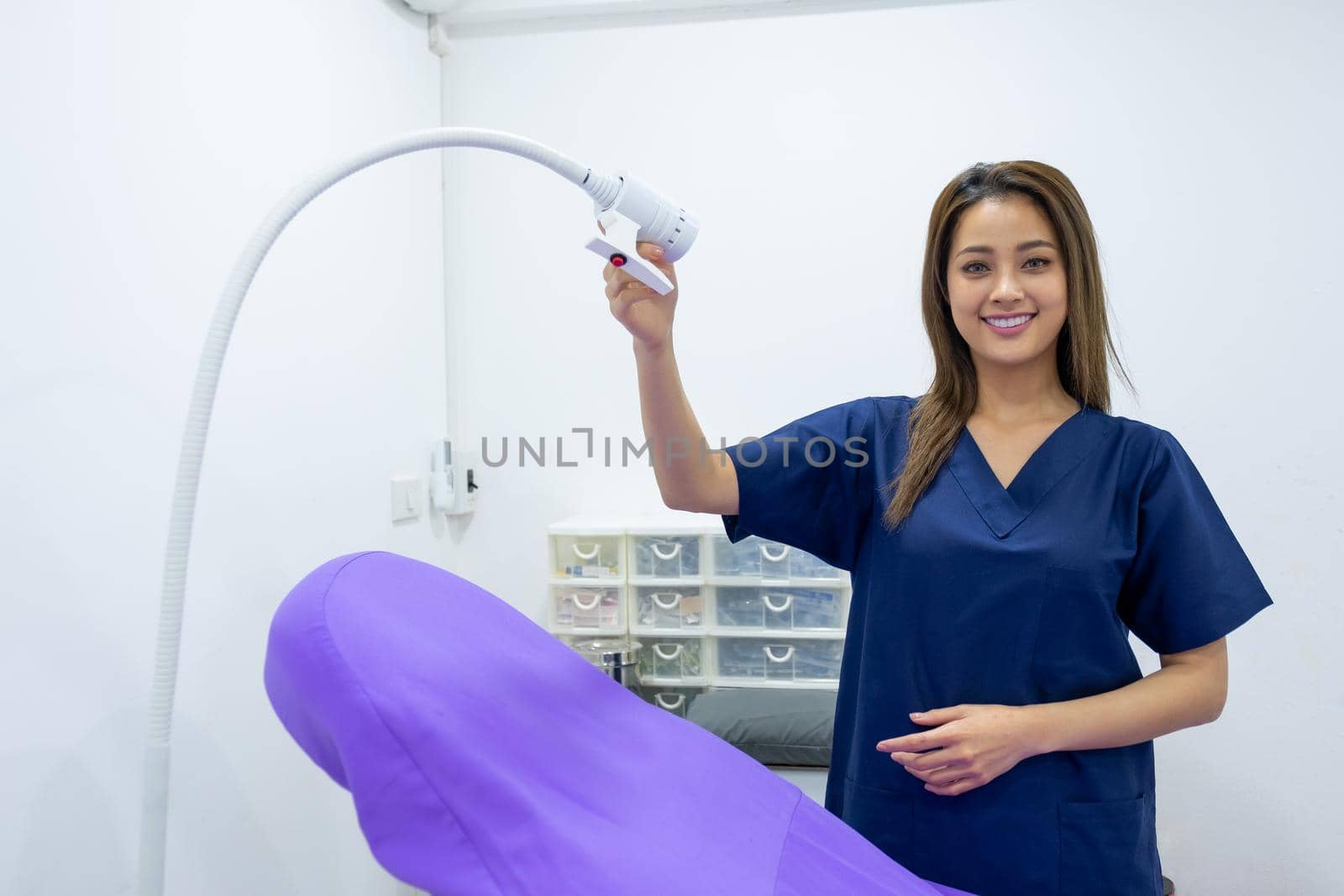 Beautiful doctor or nurse of beauty clinic hold light and stand in front of bed also smile and look to camera. Beauty business for good appearance of people concept.