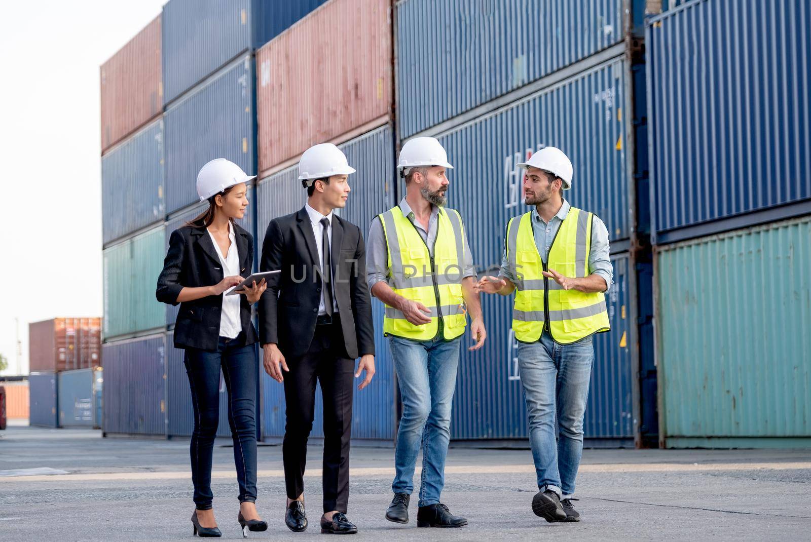 Group of cargo container workers or factory and engineer technicians walk and discuss together in workplace area. Good teamwork support best success work of industrial business concept.
