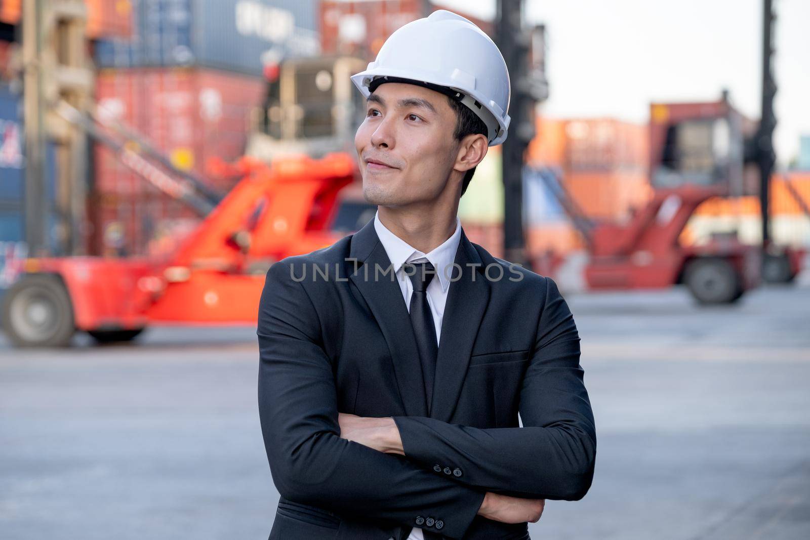 Portrait of engineer worker of factory technician with Chinese style stand in front of cargo container crane in workplace area. Concept of good support best successful for industrial business.