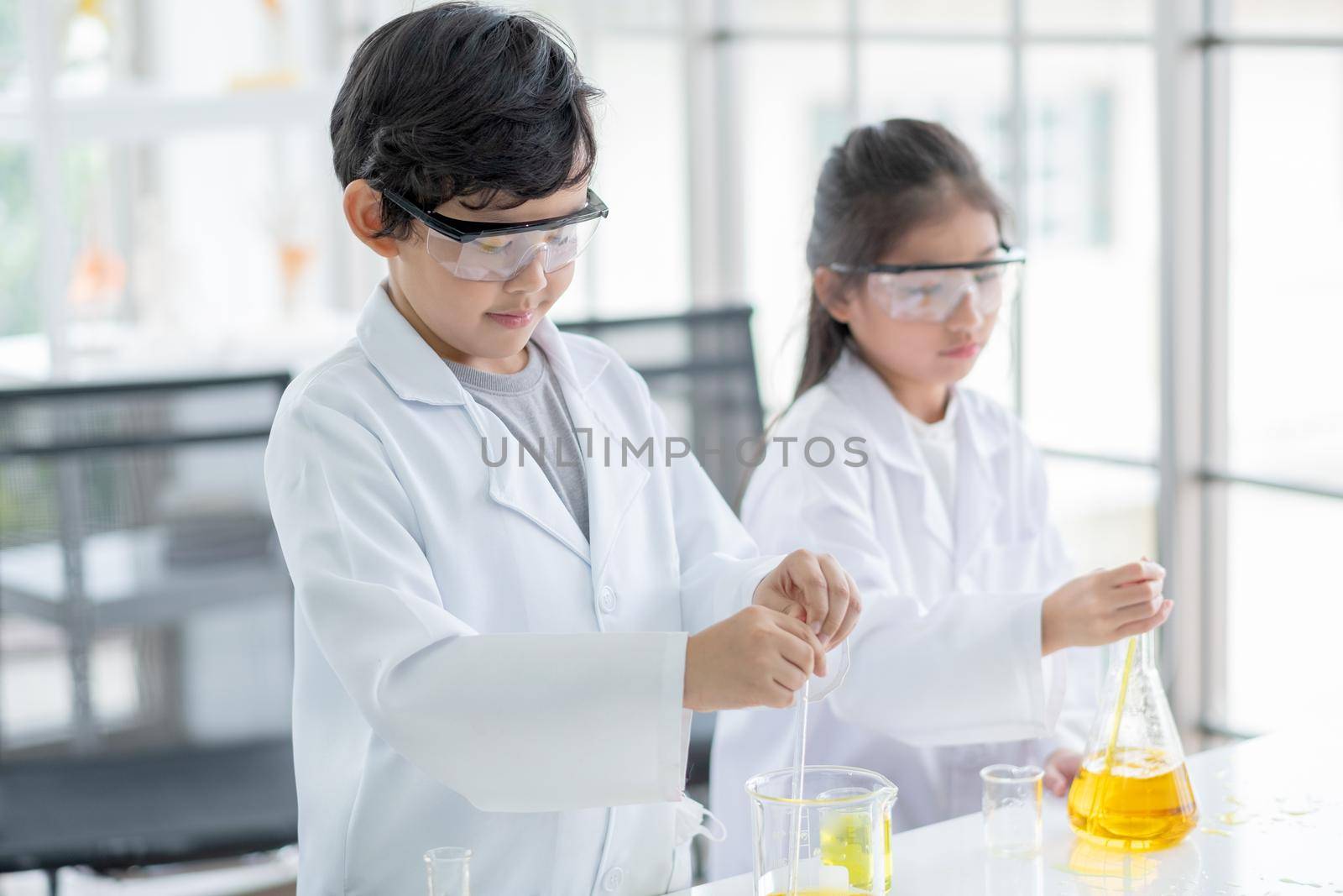 Little boy and girl scientist enjoy to examine the color chemical in laboratory by using dropper with day light. Concept of good practice and education of science for children support.