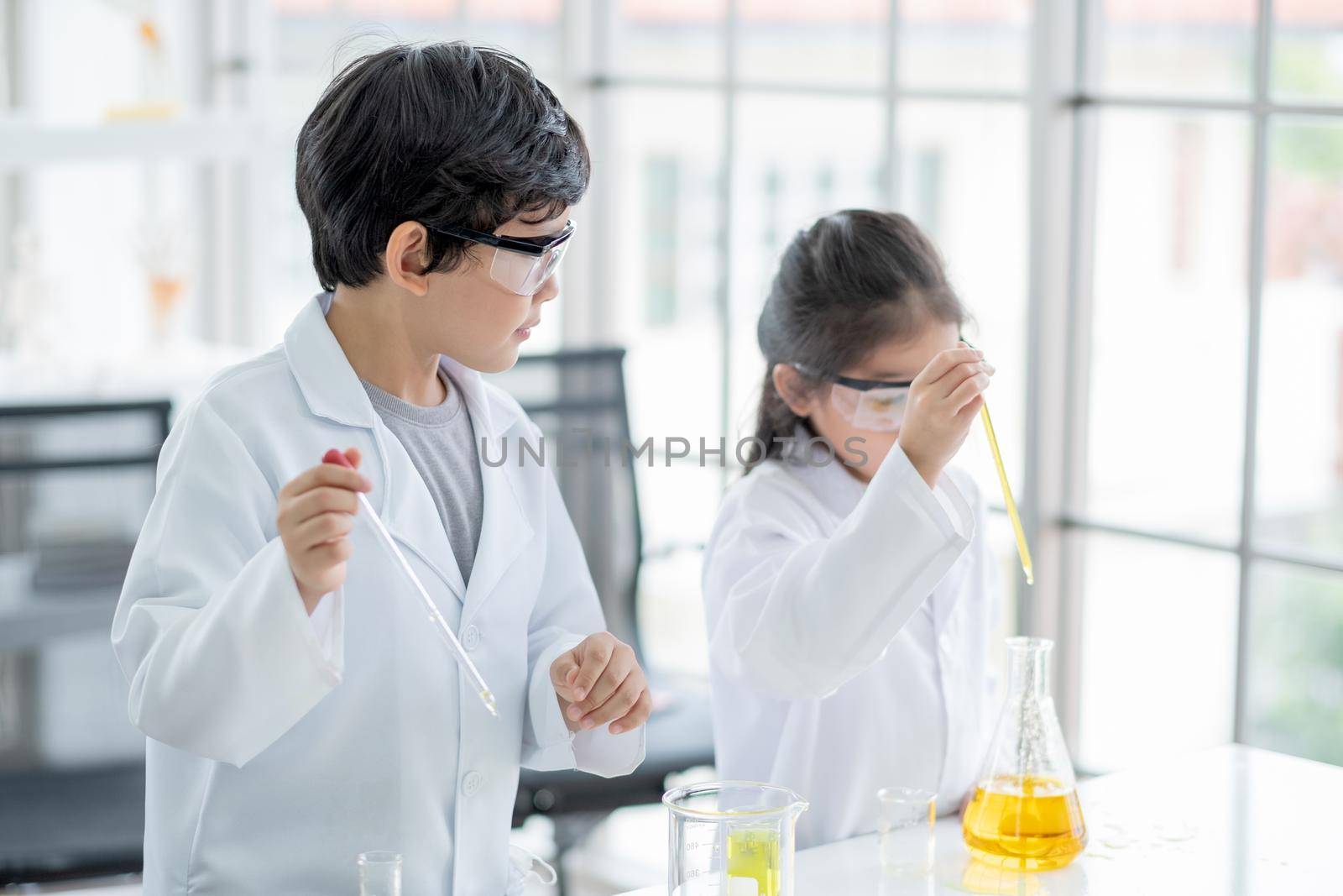 Little boy scientist enjoy to examine the color chemical in laboratory by using dropper and also interest little girl examine. Concept of good practice and education of science for children support.