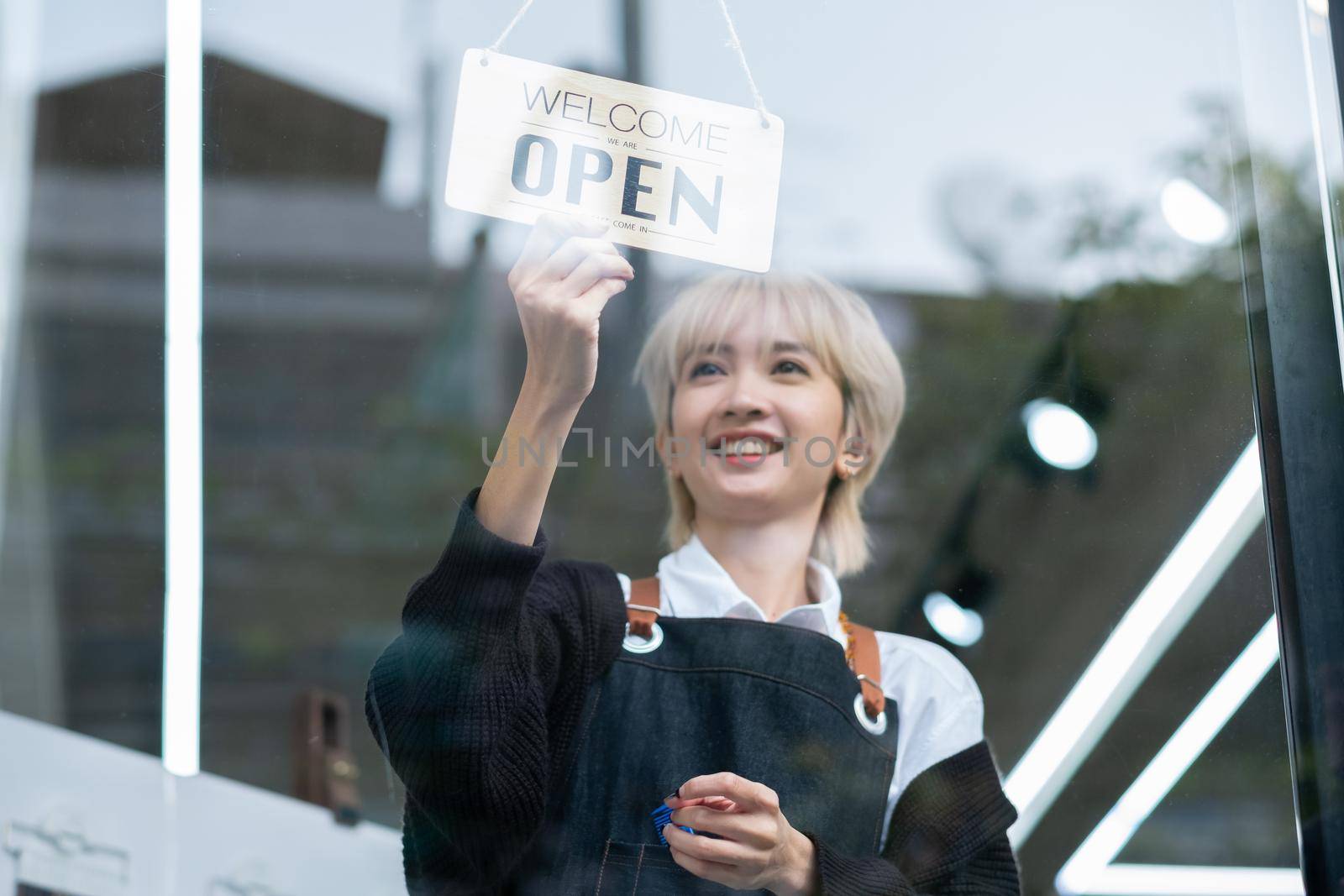 Lovely Asian beauty salon barber young girl hold banner of open the shop with smiling before work in the shop. Beauty business for good appearance for people concept.