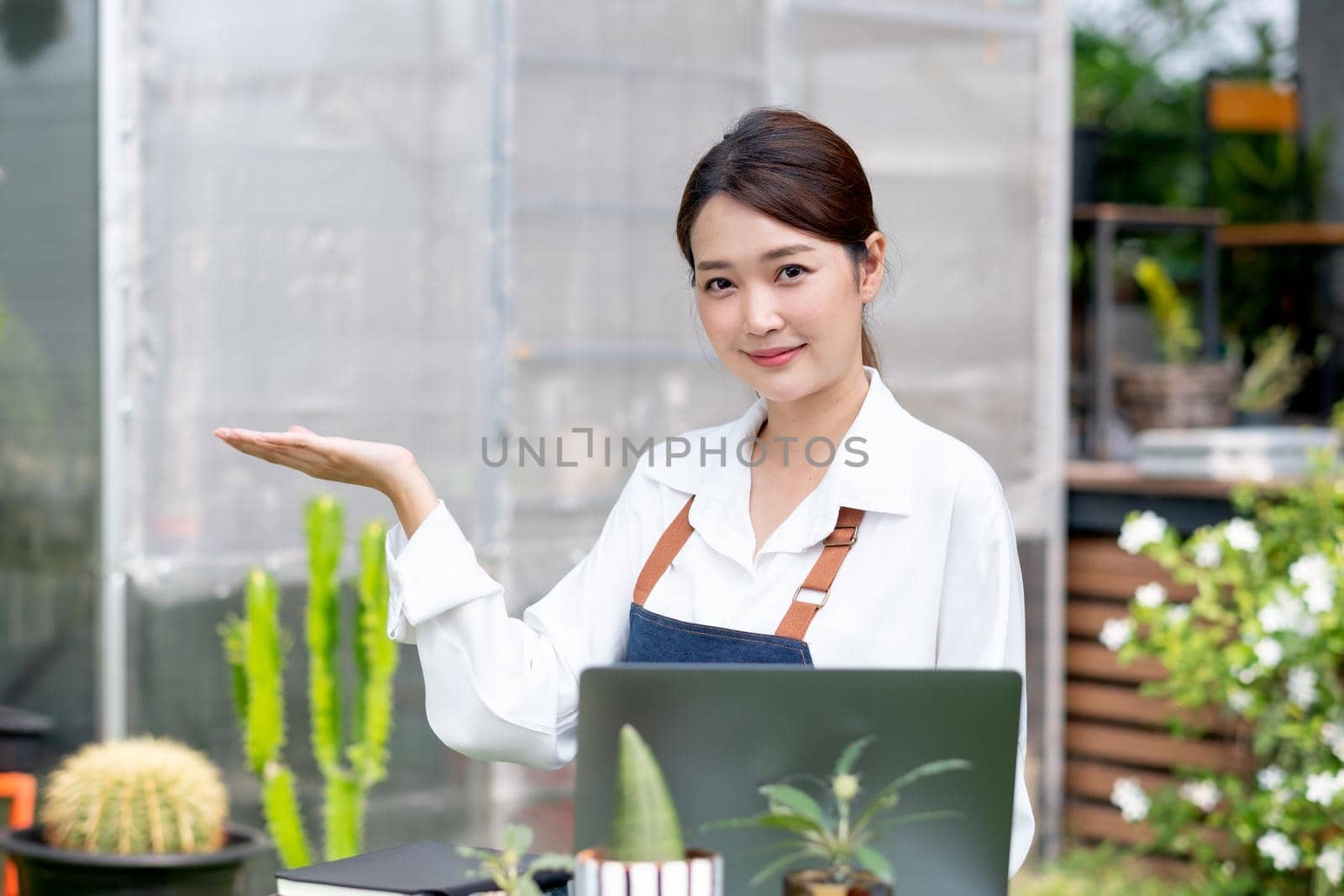 Beautiful Asian girl rest hand up look like present product and look at camera. Sustainable with small business work involve with plant of flora concept.