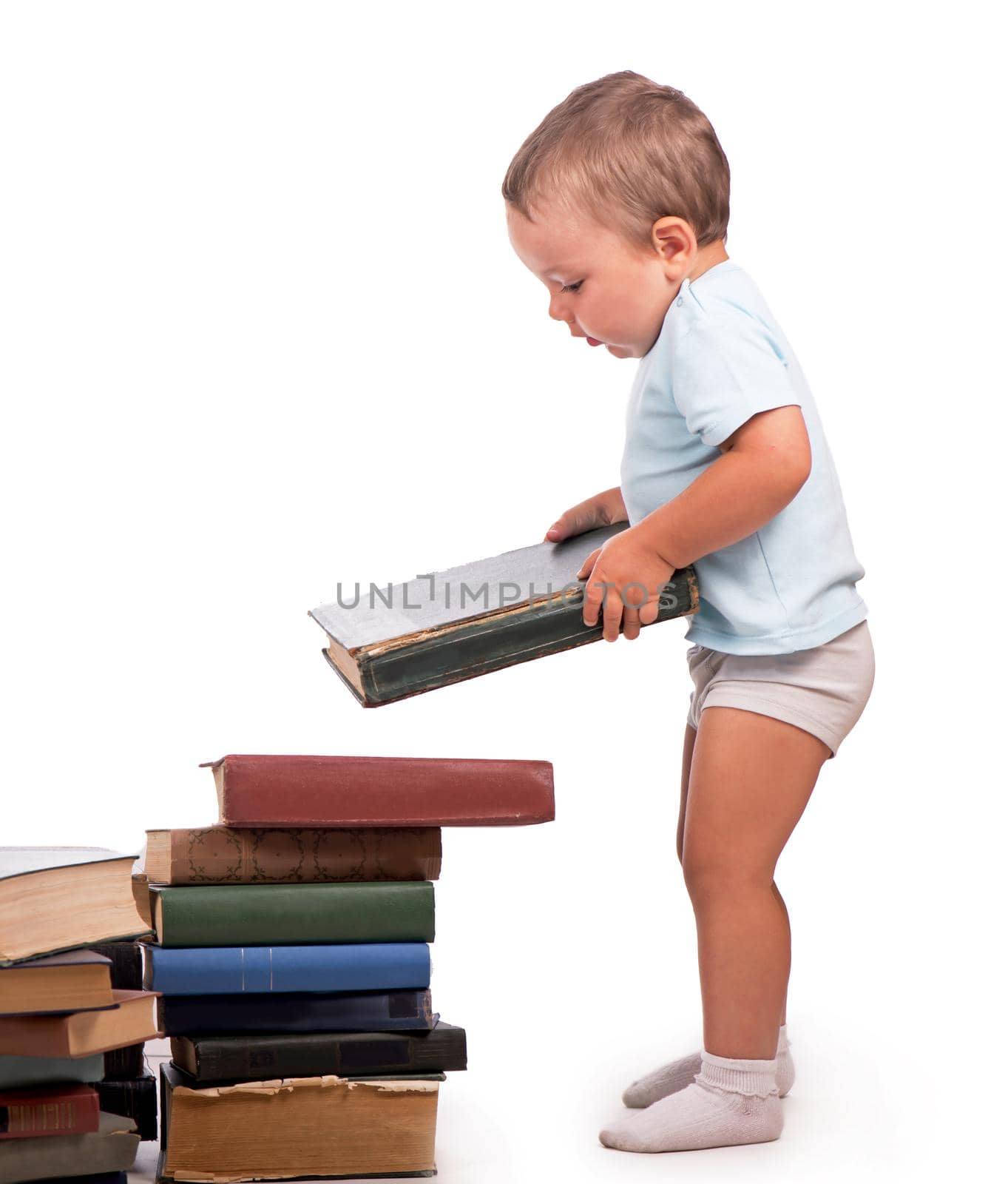 Boy stands near a stack of books for an educational portrait - isolated over white