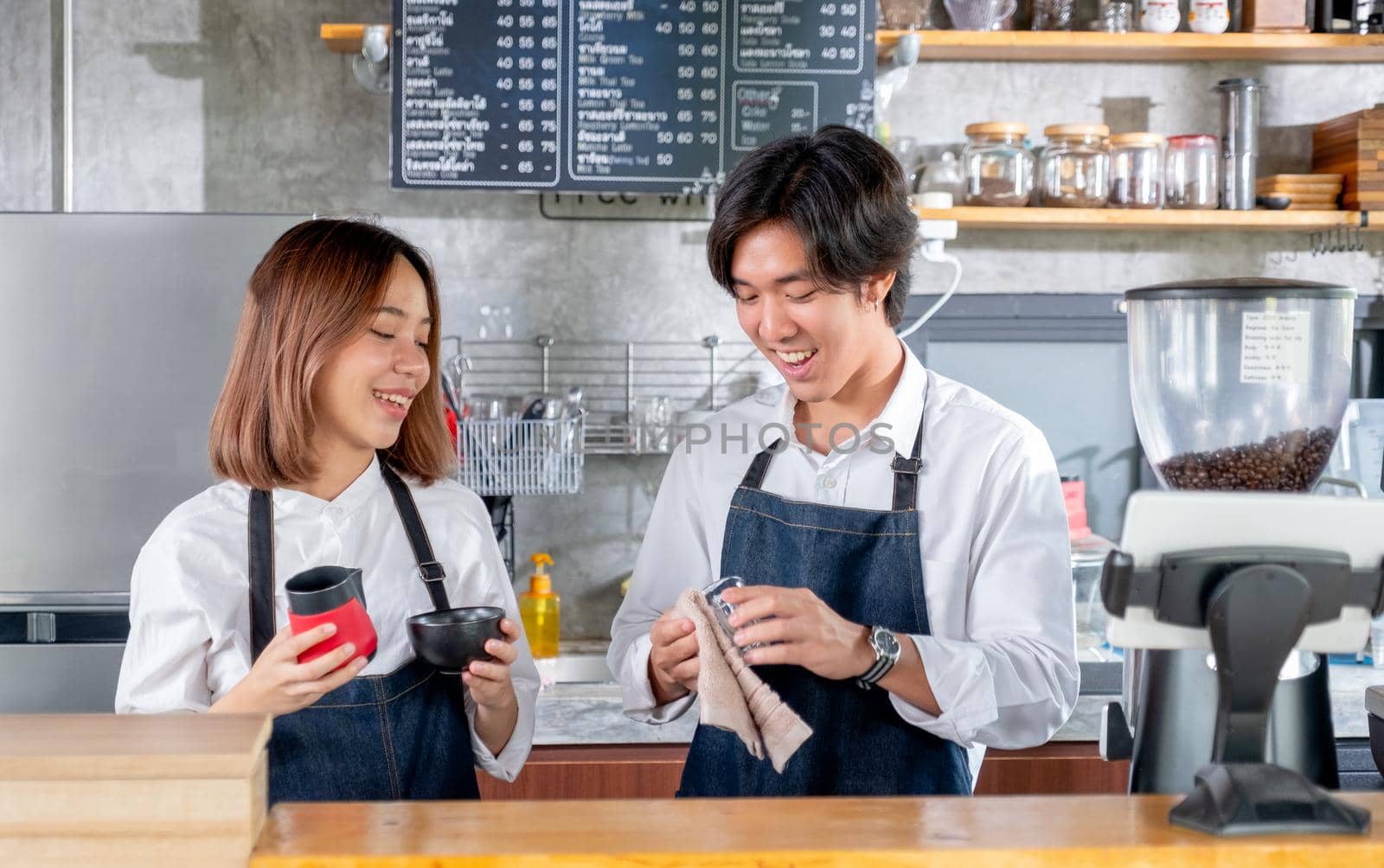 Two Asian barista or coffee maker man and woman work together in coffee shop. Concept of happy working with small business together.