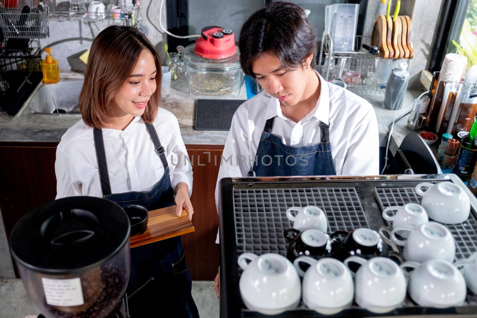 Top view of two barista or coffee maker work in front the machine with happy emotion. Happy working with small business and sustainable concept.