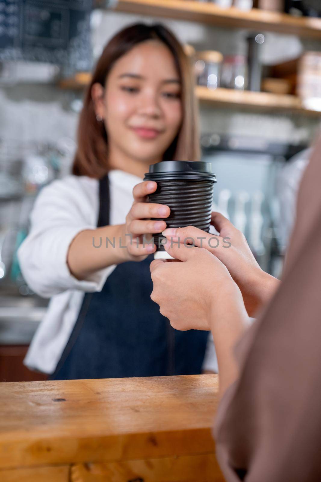 Close up hand of customer woman receive a cup of coffee from barista or coffee maker in coffee shop. Happy working with small business and sustainable concept.