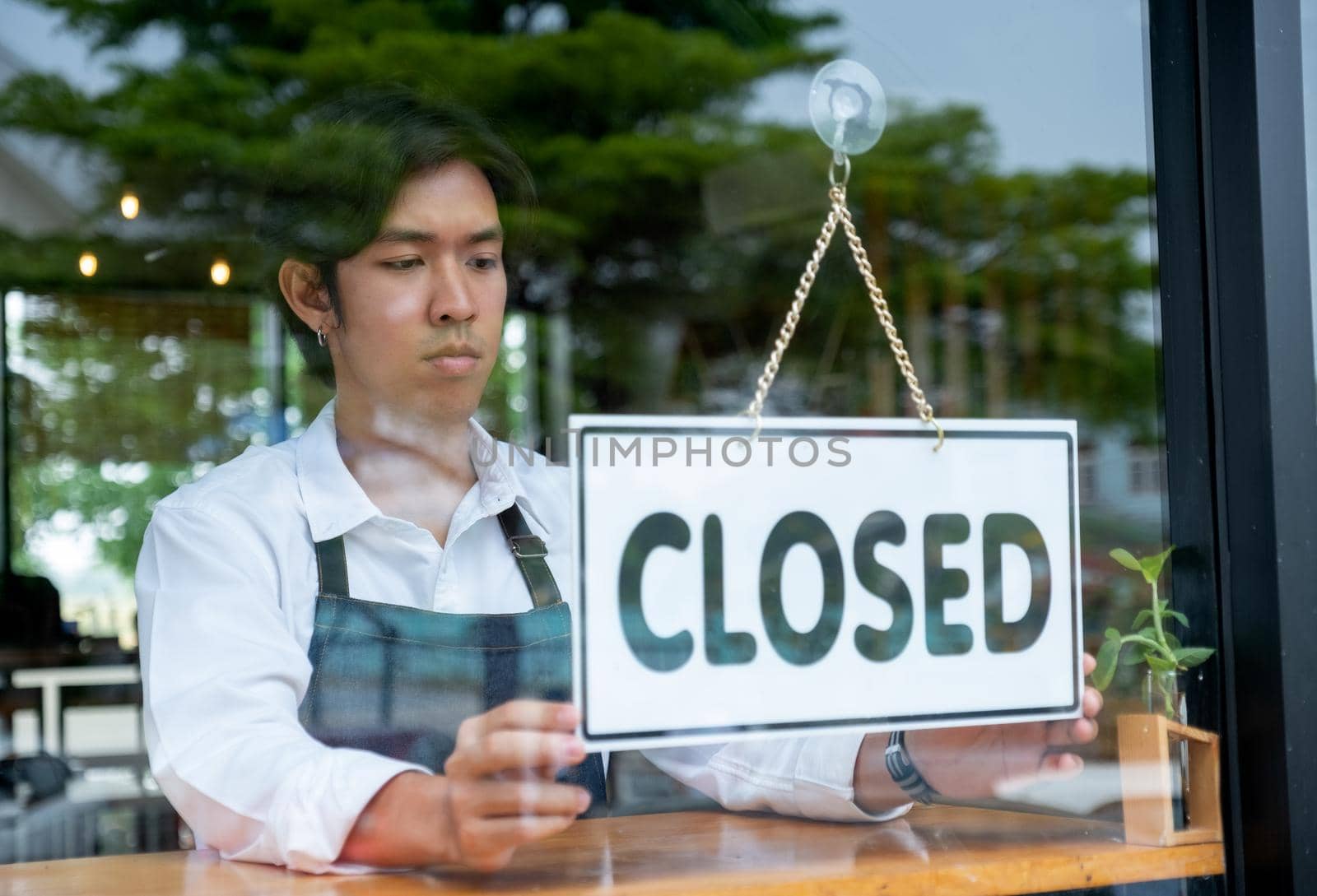 Barista or coffee maker man hold banner of closed for the symbol of no service for customer. Concept of virus pandemic and effect to people.