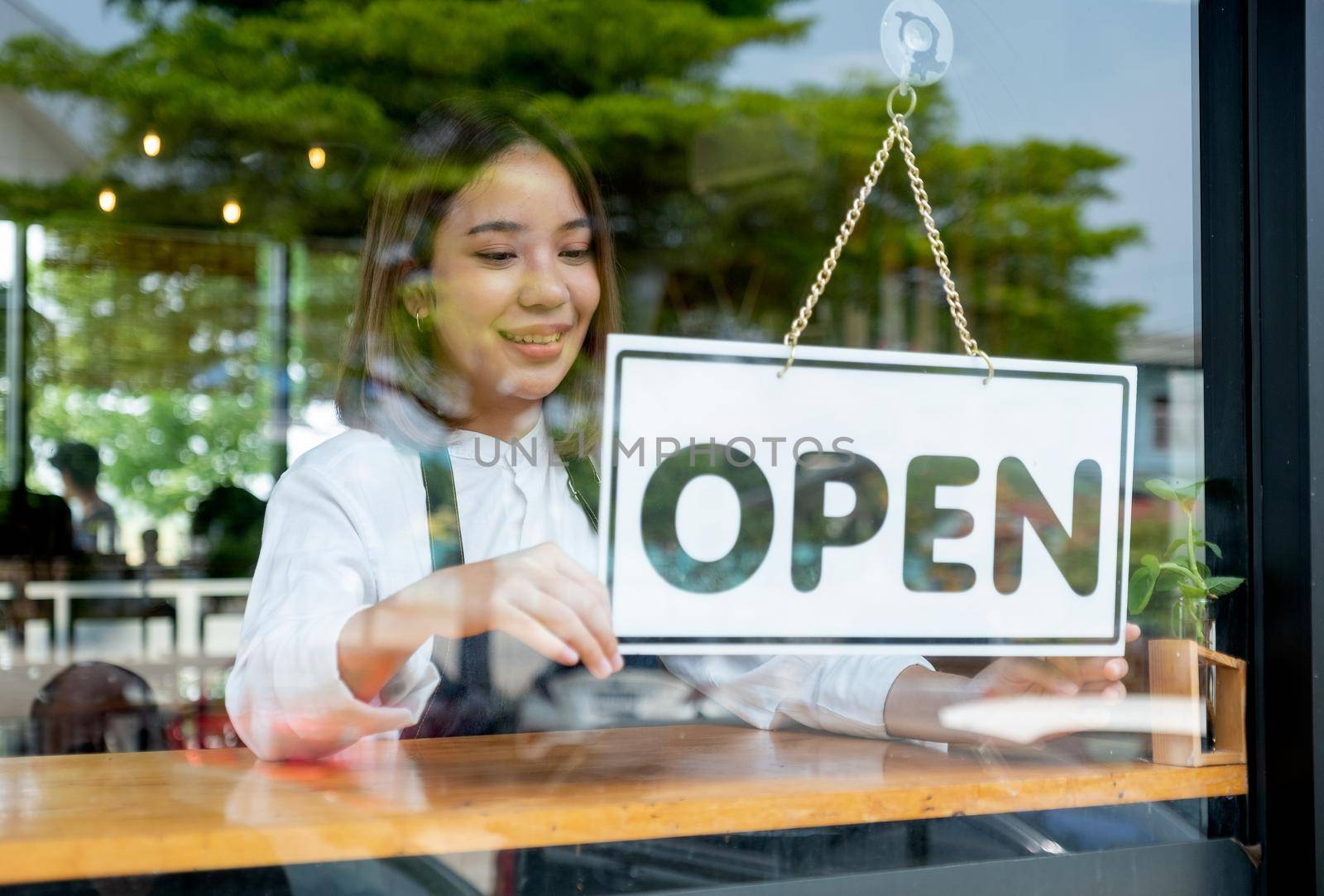 Barista or coffee maker woman hold banner of open for the symbol of ready to service for customer. Concept of happy working with small business and sustainable.