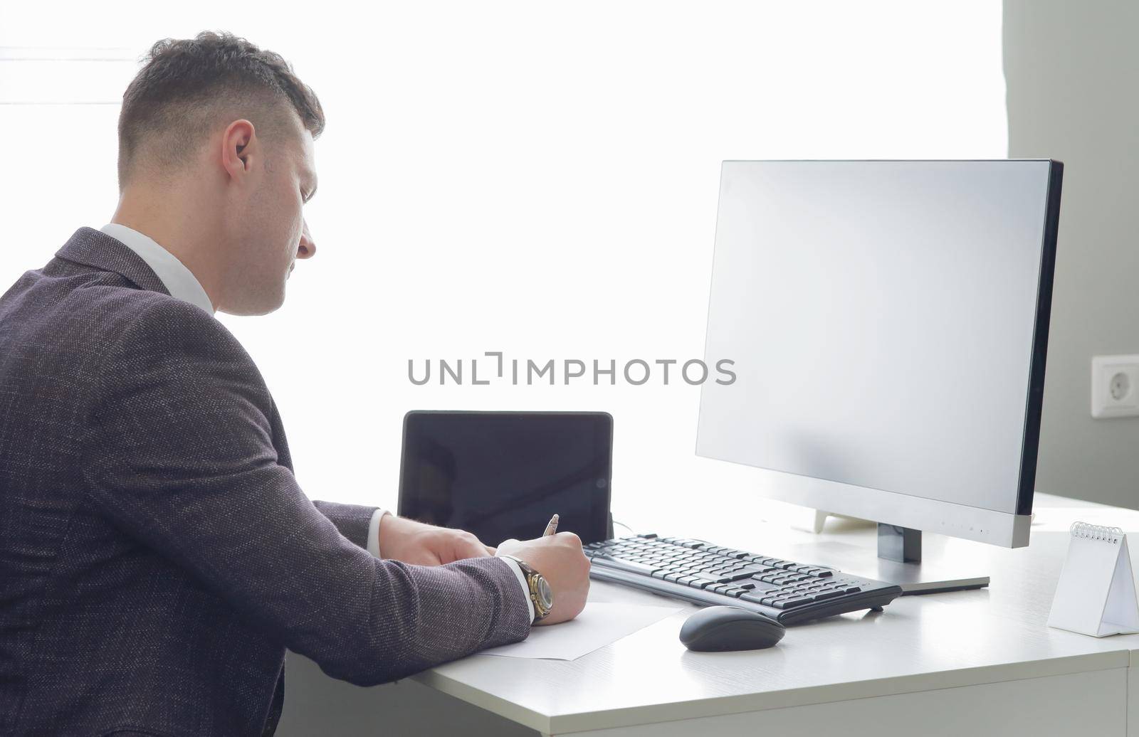 Young business man working at the computer and papers on the table by selinsmo