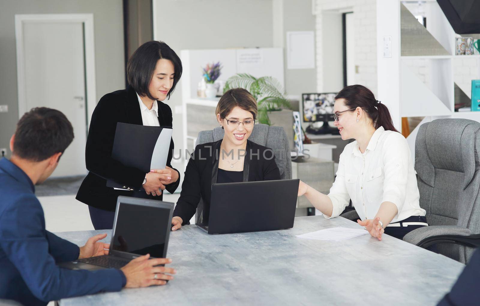 Three young successful business women in the office, together, happily working on a project by selinsmo