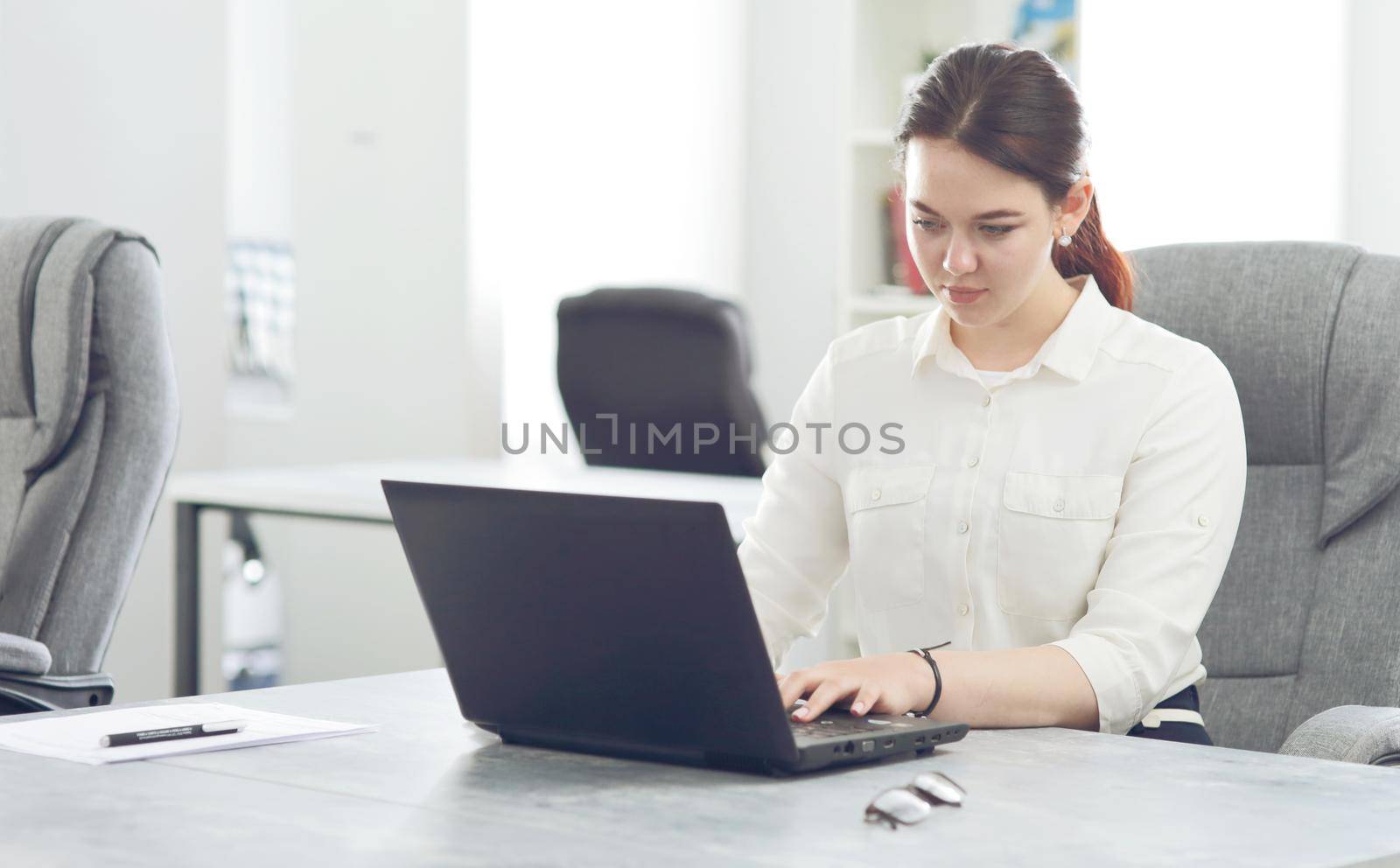 Young attractive business woman working in office smiling looking into laptop. 