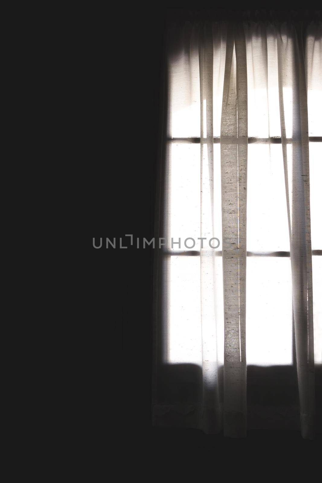 Transparent curtain with big window behind taken from room interior. Soft light shining through window. Shadows and lights. Space for text.