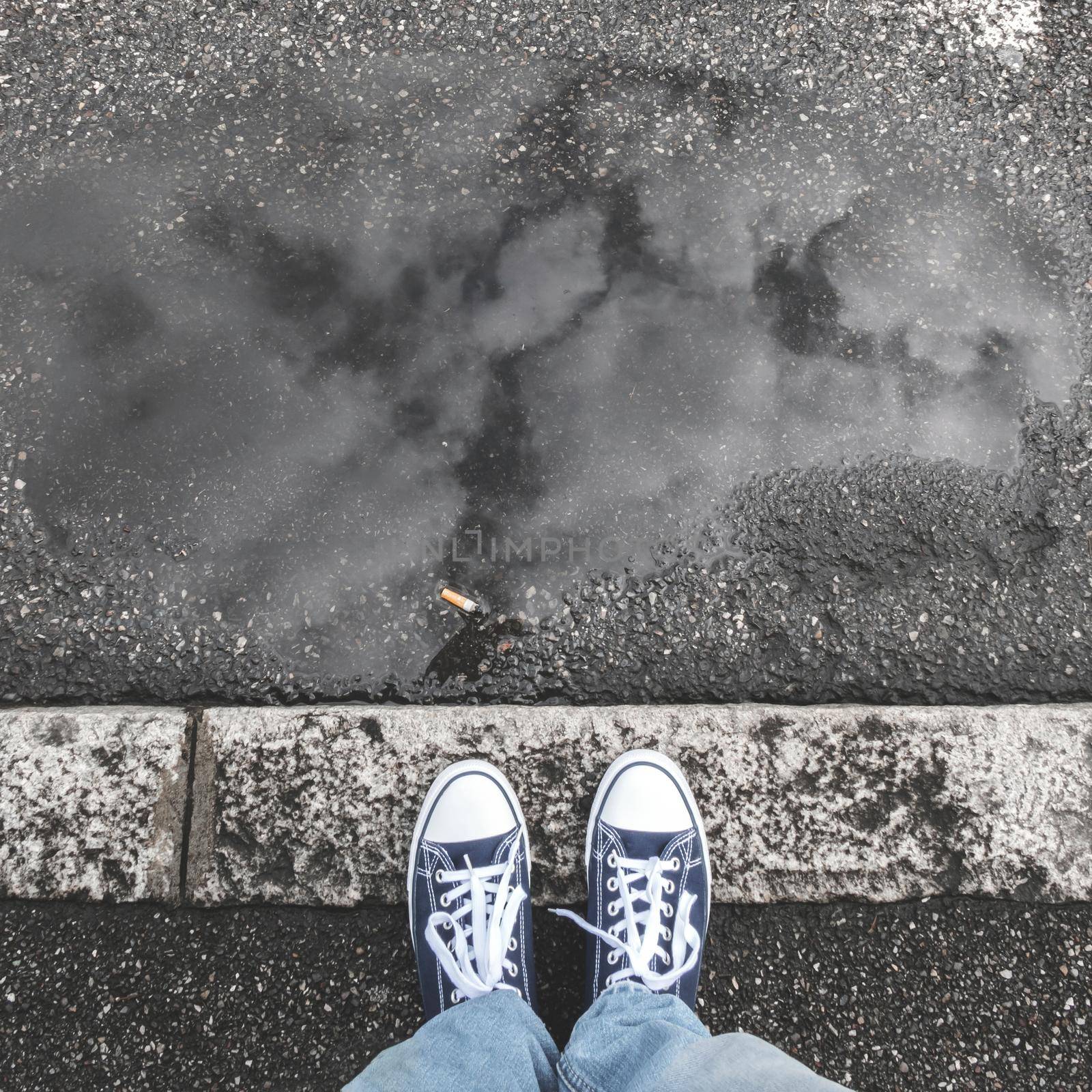 Feet on sidewalk. Feet of a man in sneakers shoes standing on gray sidewalk. Top view. Ideal for concepts.