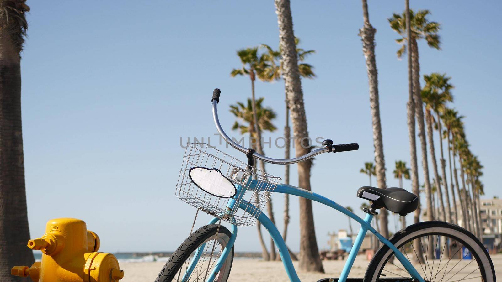 Bicycle cruiser bike by ocean beach, California coast USA. Summer cycle, lifeguard hut and palm tree by DogoraSun