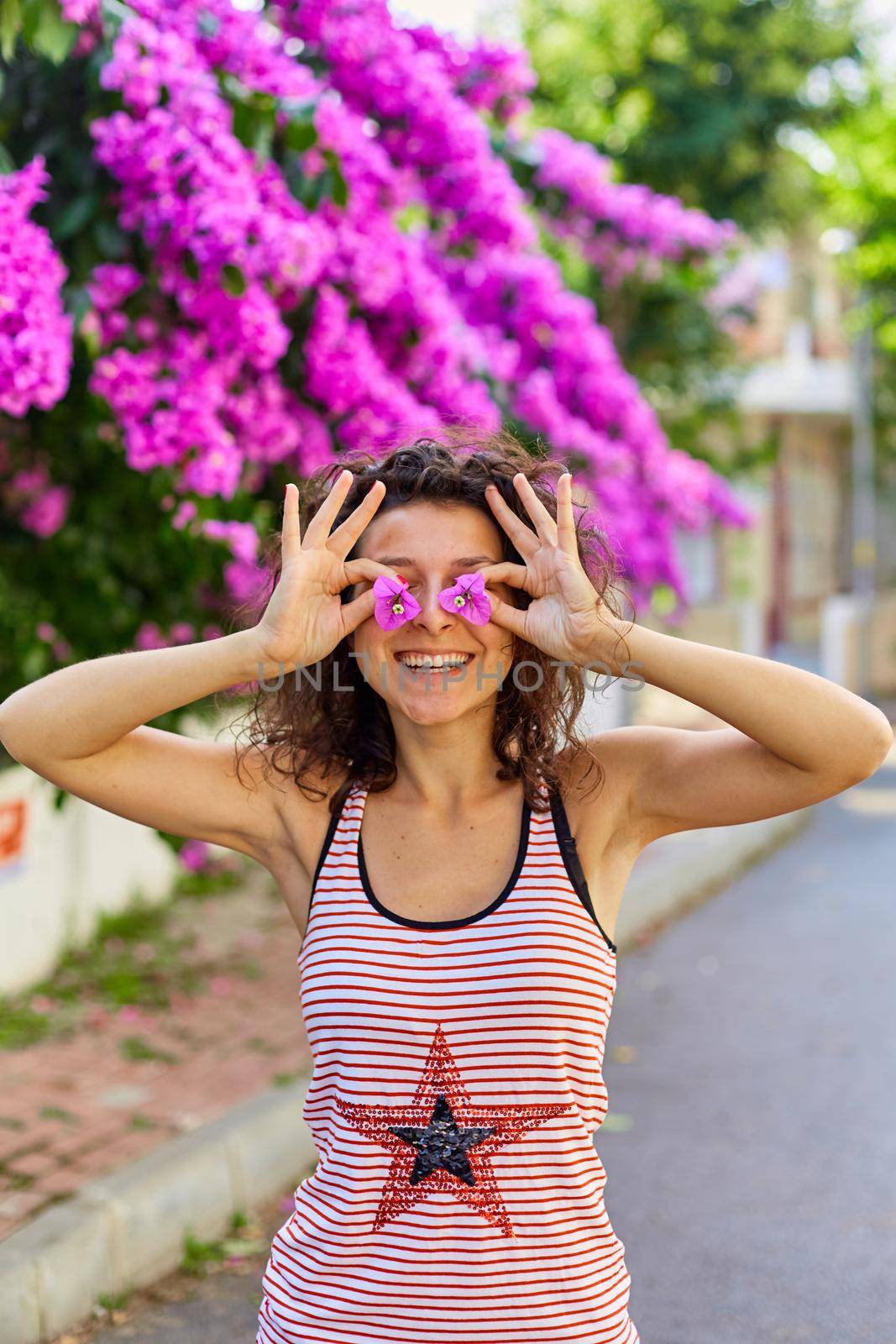 Beautiful young girl model brunette posing with blooming purple flowers in Turkey on the island of Buyukada.