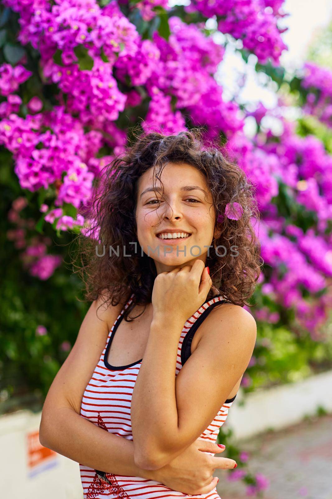 Beautiful young girl model brunette posing with blooming purple flowers in Turkey on the island of Buyukada.