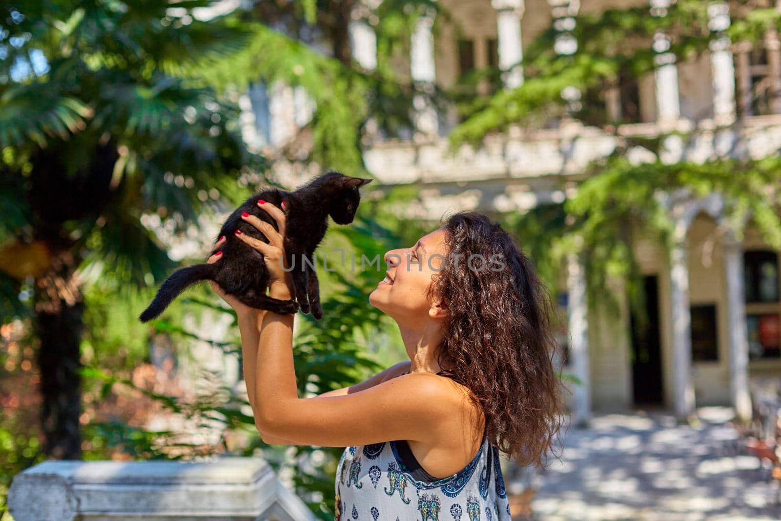 A young girl plays with a black kitten she found on the street.