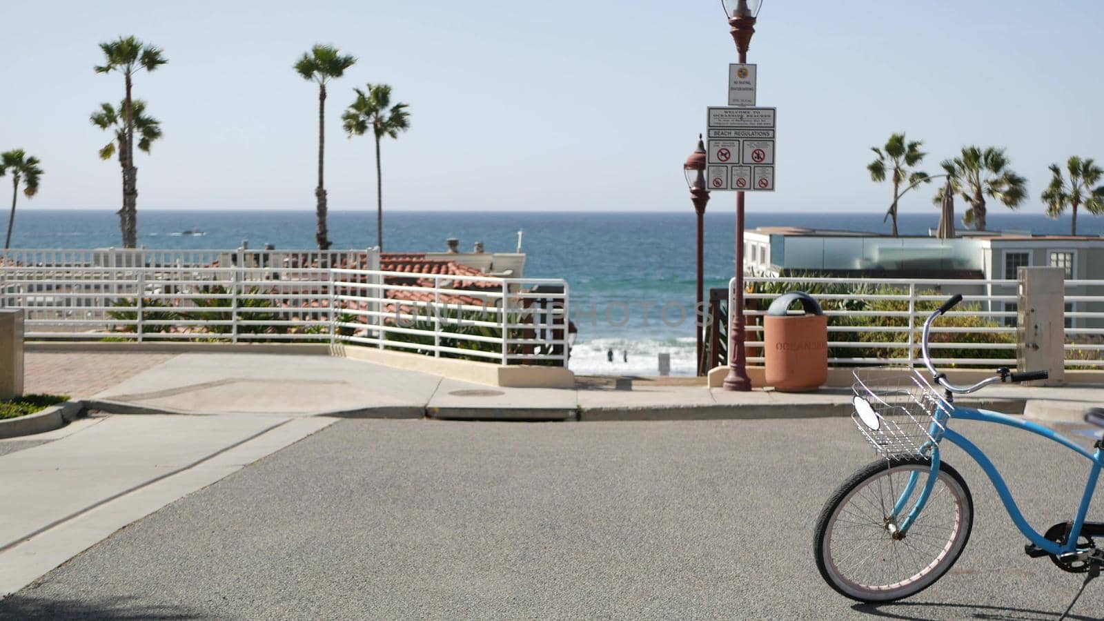 Blue bicycle, cruiser bike by ocean beach, pacific coast, Oceanside California USA. Summertime vacations on sea shore. Vintage cycle near wooden stairs, stairway access. Staircase, tropical palm trees