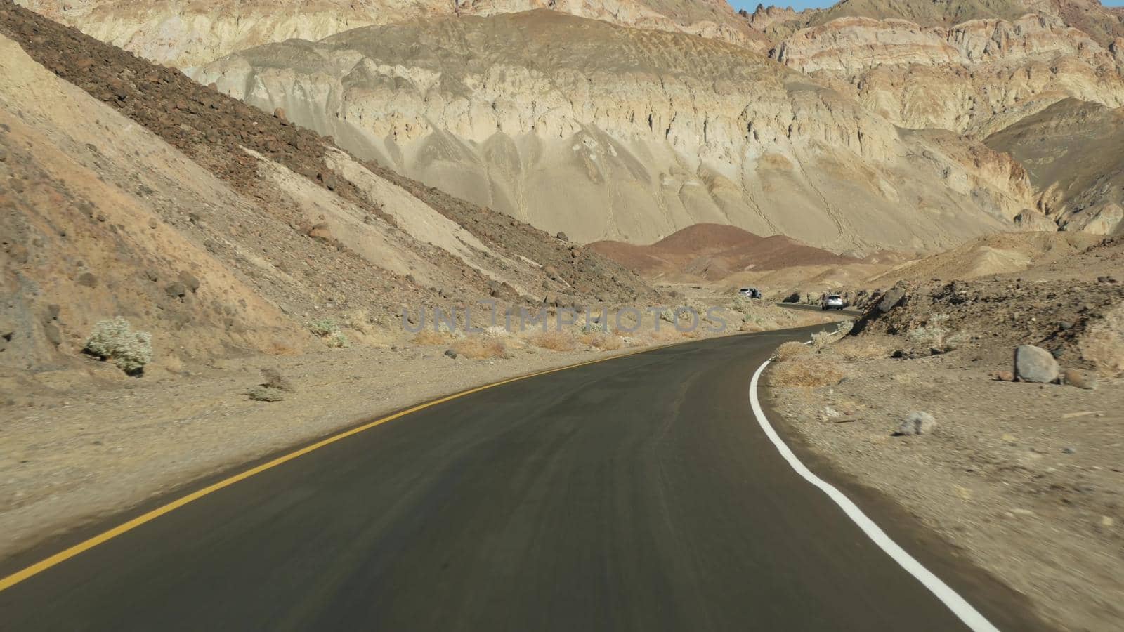 Road trip to Death Valley, Artists Palette drive, California USA. Hitchhiking auto traveling in America. Highway, colorful bare mountains and arid climate wilderness. View from car. Journey to Nevada.