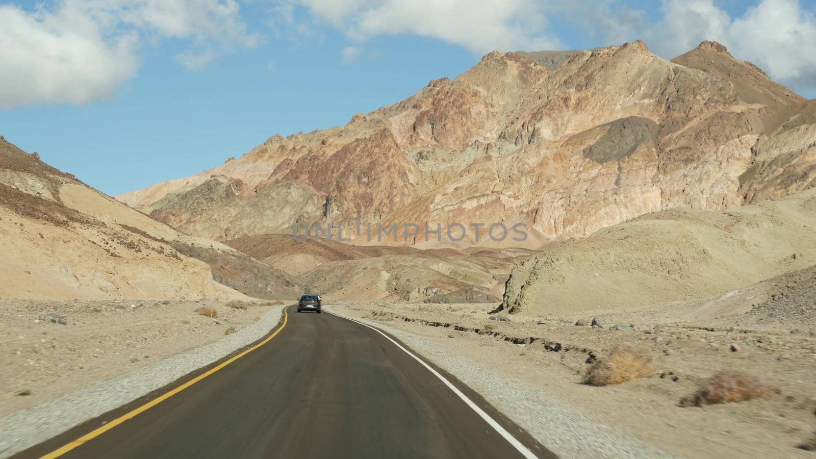 Road trip to Death Valley, Artists Palette drive, California USA. Hitchhiking auto traveling in America. Highway, colorful bare mountains and arid climate wilderness. View from car. Journey to Nevada.