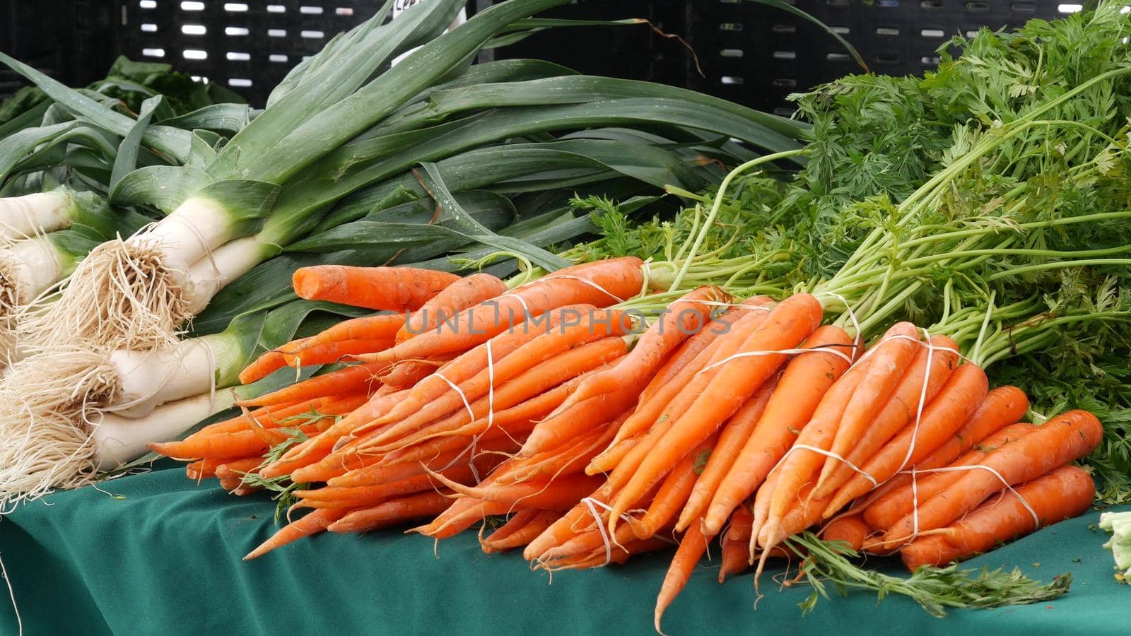 Organic vegetables on counter, fresh local produce homegrown raw veggies on marketplace stall. Healthy vegetarian food, Farmers market in Oceanside California USA. Agricultural farm harvest selling.