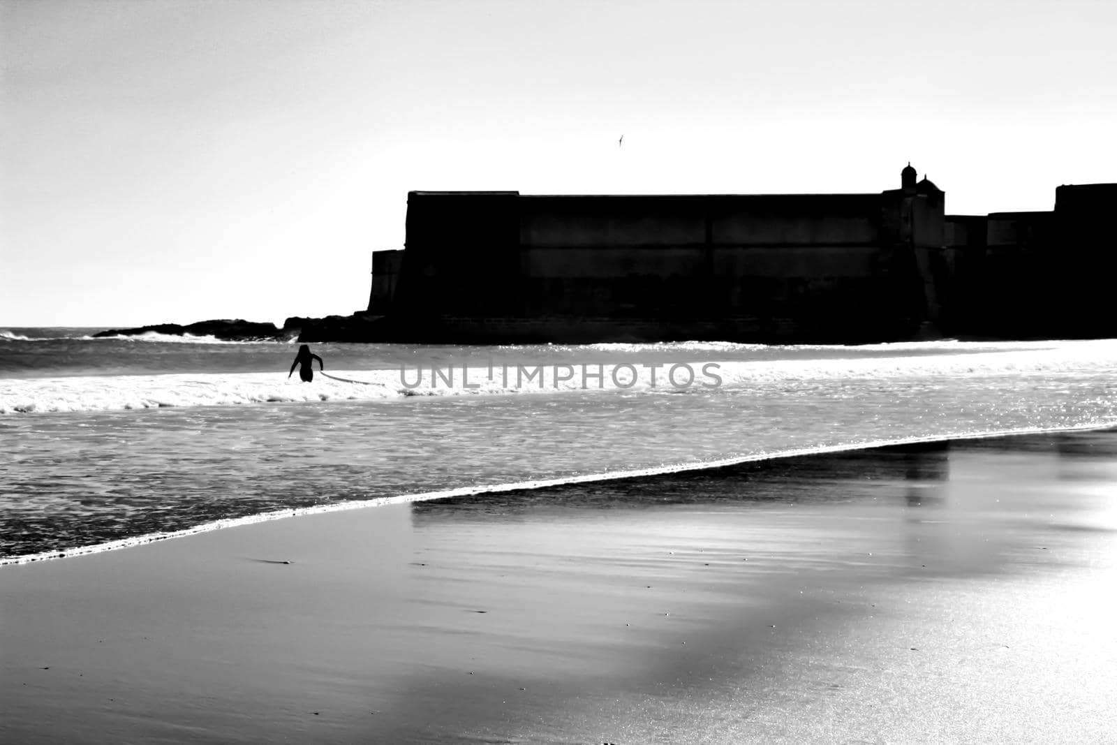 Beautiful beach called Praia da Torre in Lisbon, Portugal, in a sunny day of Spring. Surfers playing with the waves.
