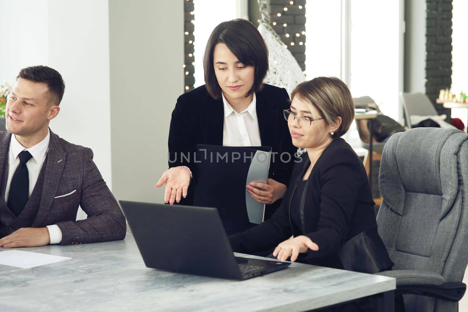 Two young business women in the office, analyzing information looking into a laptop. 