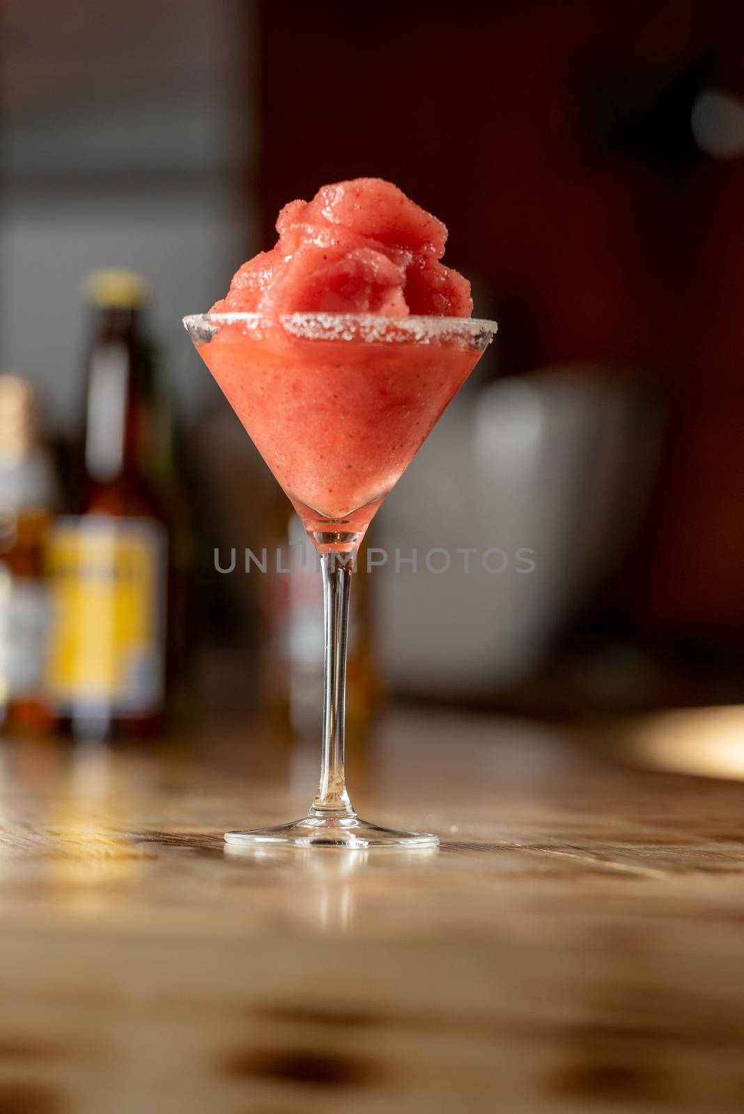 Frozen margarita cocktail on wooden bar.