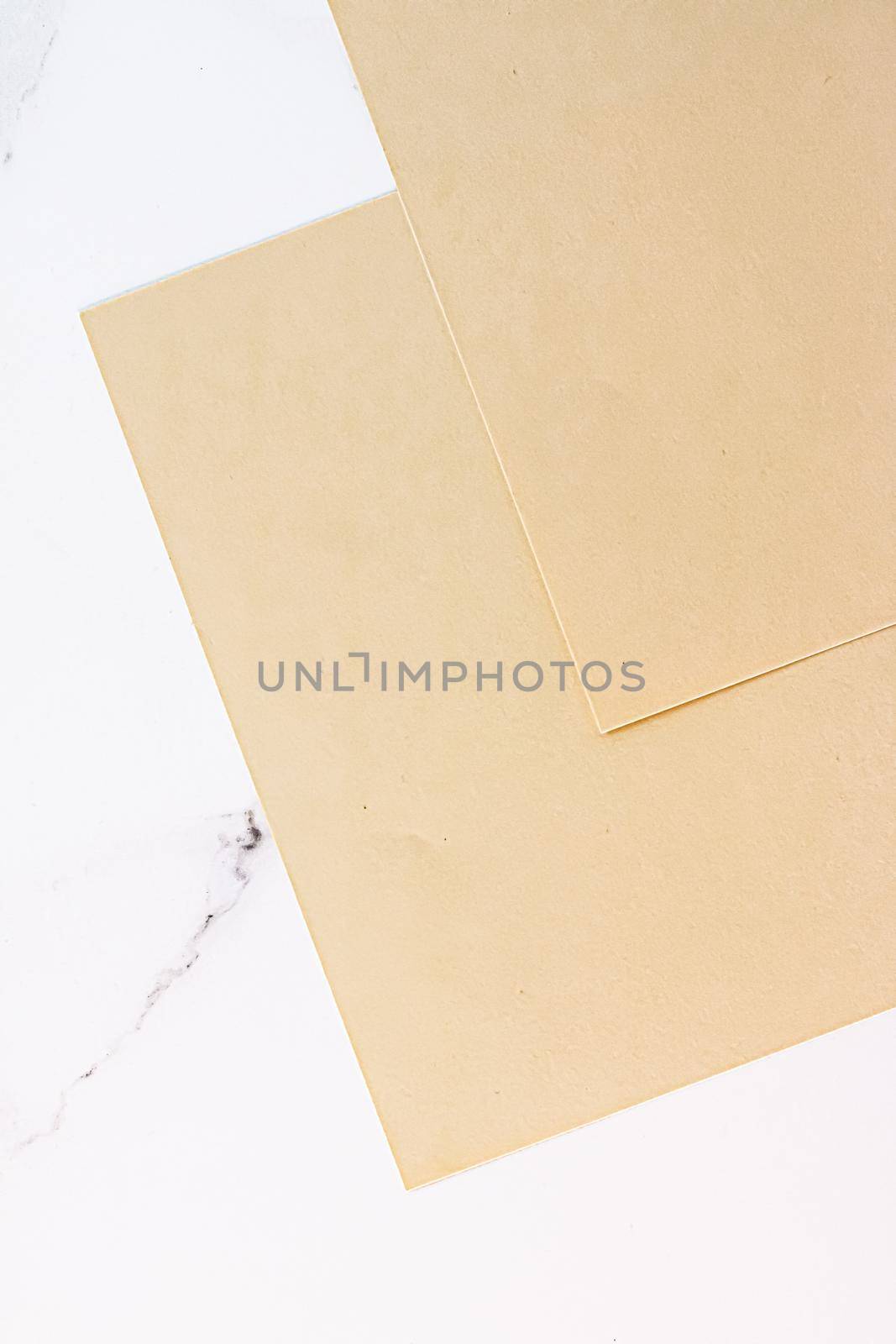 Beige A4 papers on white marble background as office stationery flatlay, luxury branding flat lay and brand identity design for mockup by Anneleven