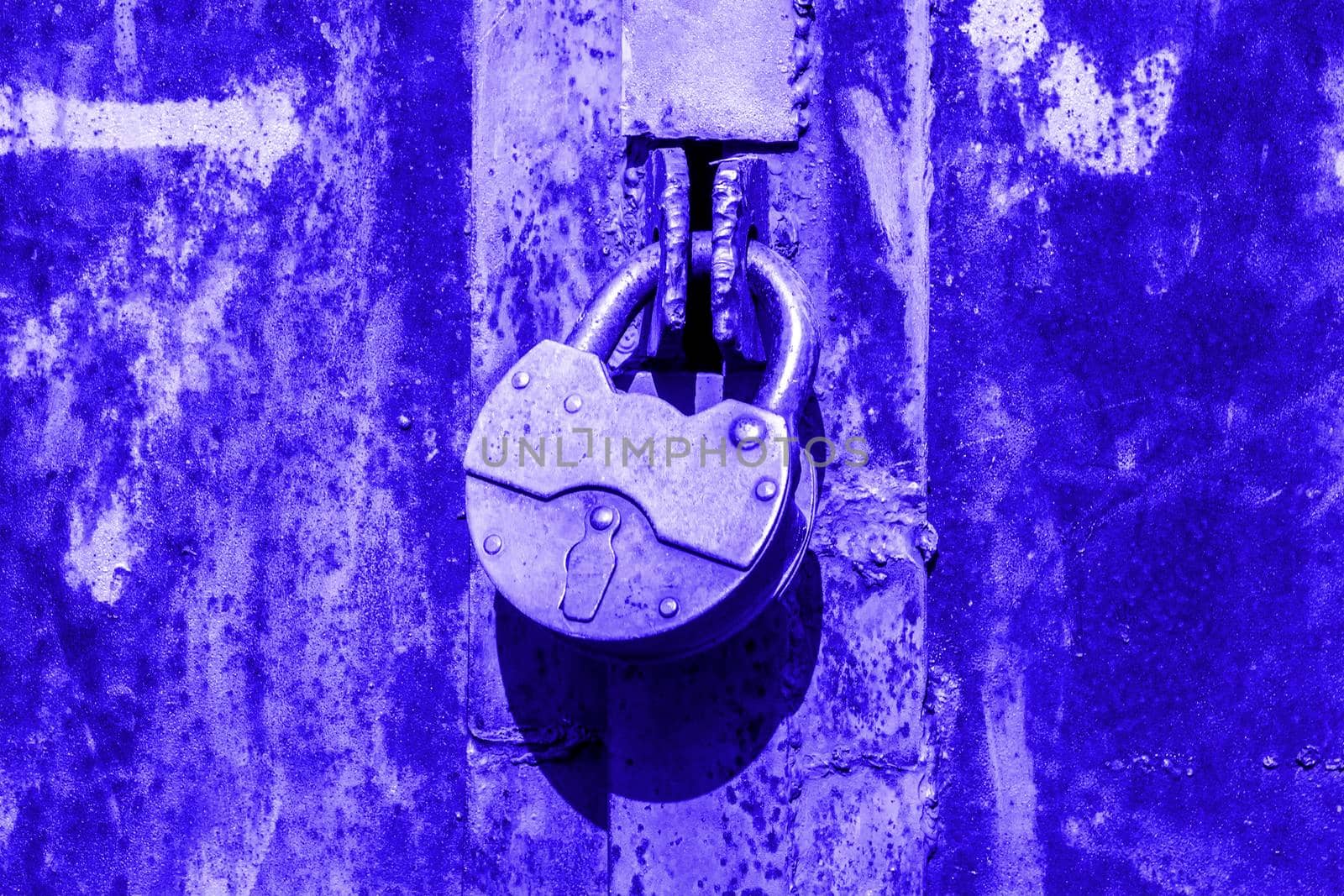 Iron lock on rusty doors. Sunny autumn day. Front view. Blue toned. by Essffes