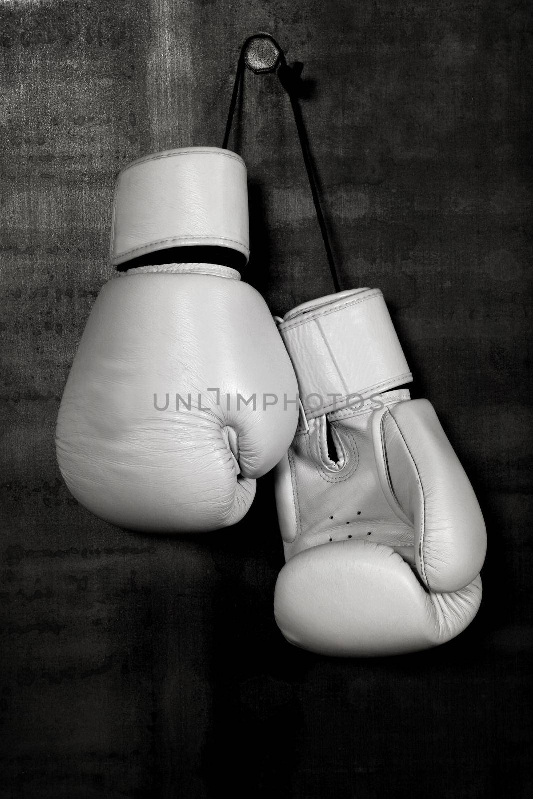 White leather boxing gloves hanging on black wall by BreakingTheWalls