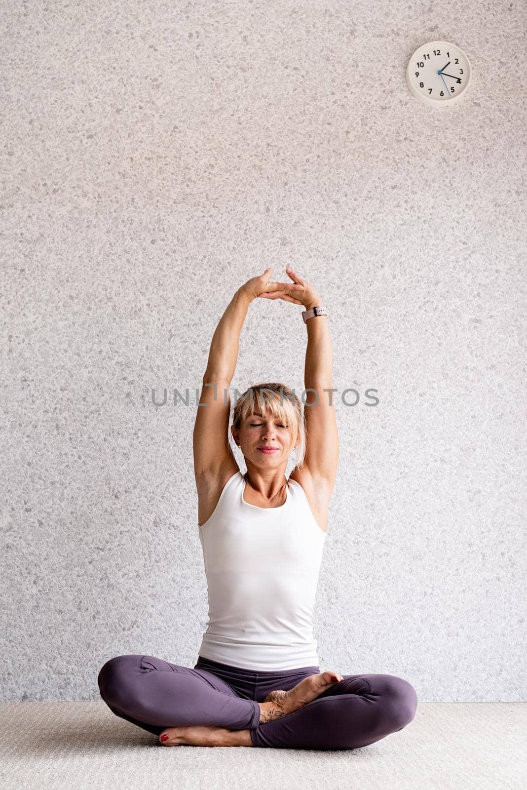 attractive woman practicing yoga at home, wearing sportswear, white shirt and purple pants by Desperada