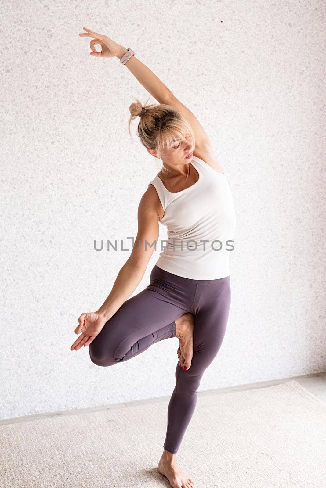 Active lifestyle. Young attractive woman wearing sportswear practicing yoga at home. Indoor full length, gray background. Mock up t-shirt