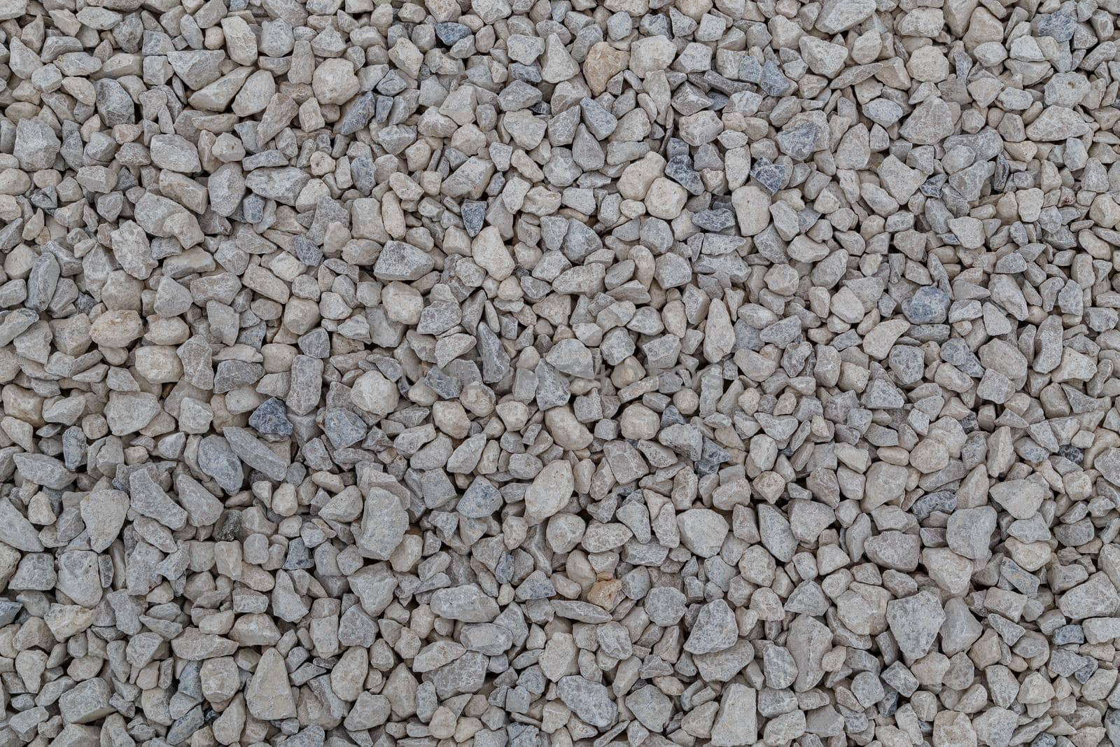 Dry white limestone ballast flat full frame background. Small gray dusty broken macadam stones texture. Viiew from above.
