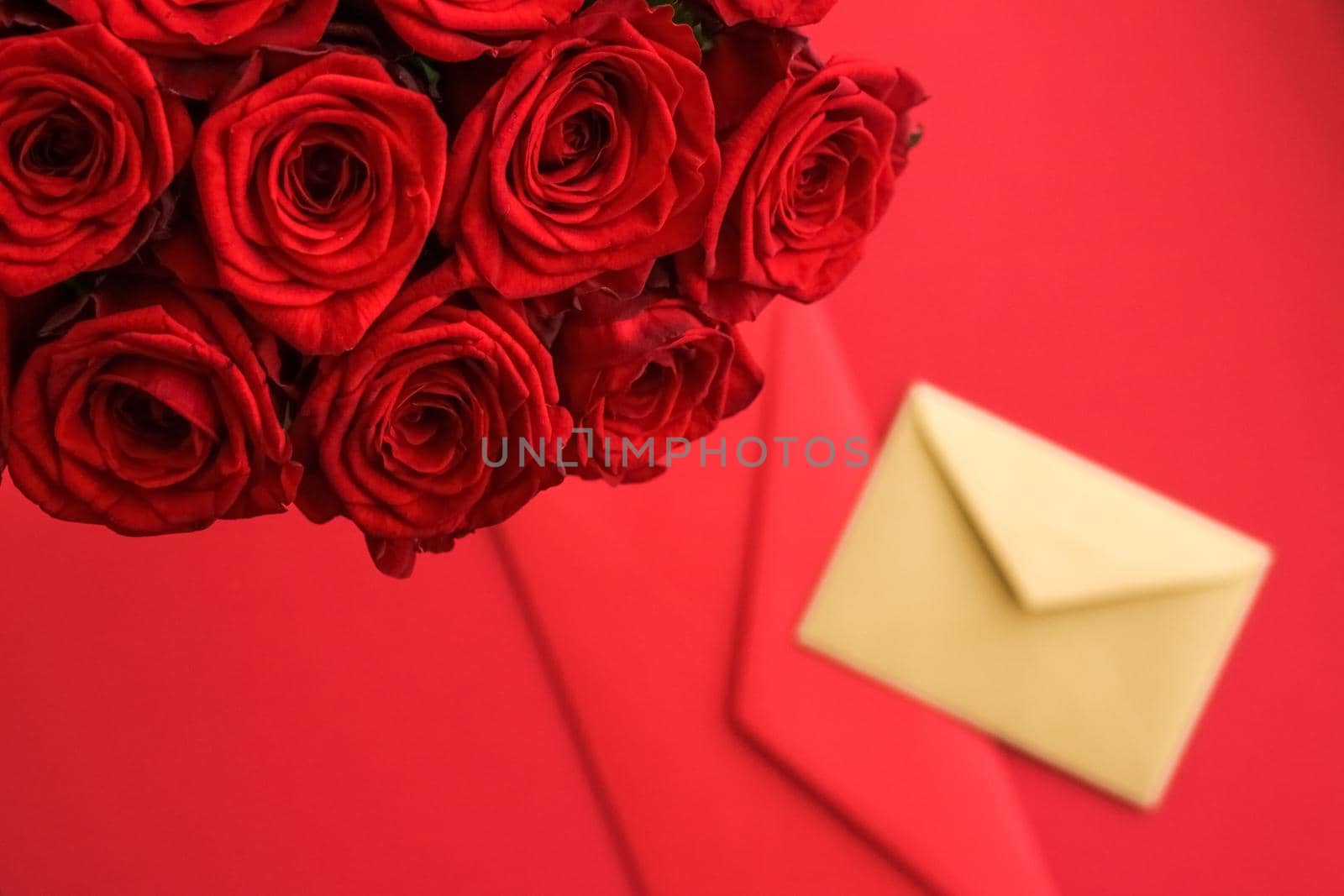 Holiday gift, flowers flatlay and happy relationship concept - Love letter and flower delivery service on Valentines Day, luxury bouquet of red roses and card envelopes on red background