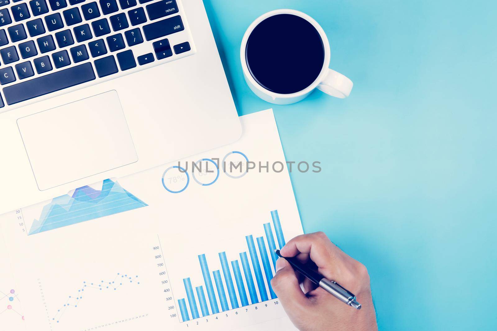 Hand of businessman looking documents report statistic financial with graph and chart and laptop computer and coffee on desk, finance and invest, digital marketing, business and communication concept.