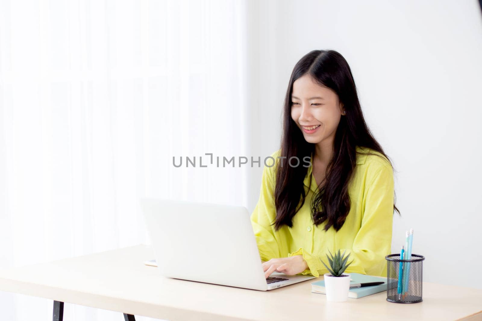 Young asian businesswoman working on laptop computer on desk at home office, freelance looking and typing on notebook on table, lifestyle of woman studying online, business and education concept.