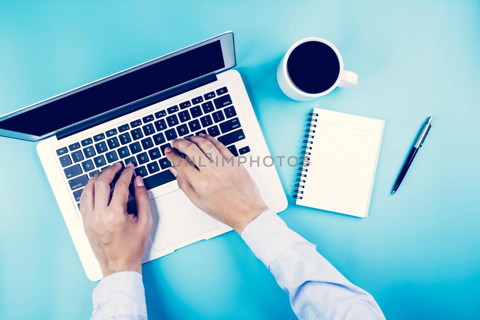 Flat lay, hand of businessman working on laptop computer with cup of coffee on desk in office, workplace and notebook and book on blue background, workspace and copy space, top view, business concept.