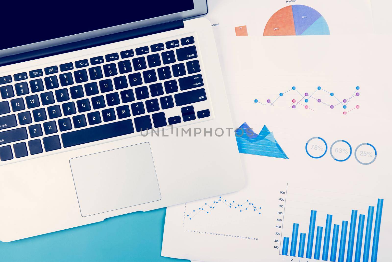 Laptop computer and documents report statistic financial with graph and chart on desk office, finance and invest, digital marketing and growth of revenue, business and communication concept.