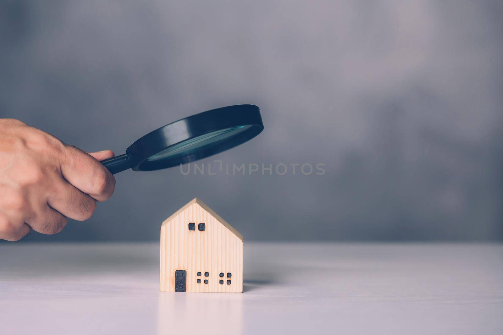 Hand of businessman hold magnifying glass looking house for examining and analyzing quality, inspection and check home, purchase and search residential and investment, business and property concept.