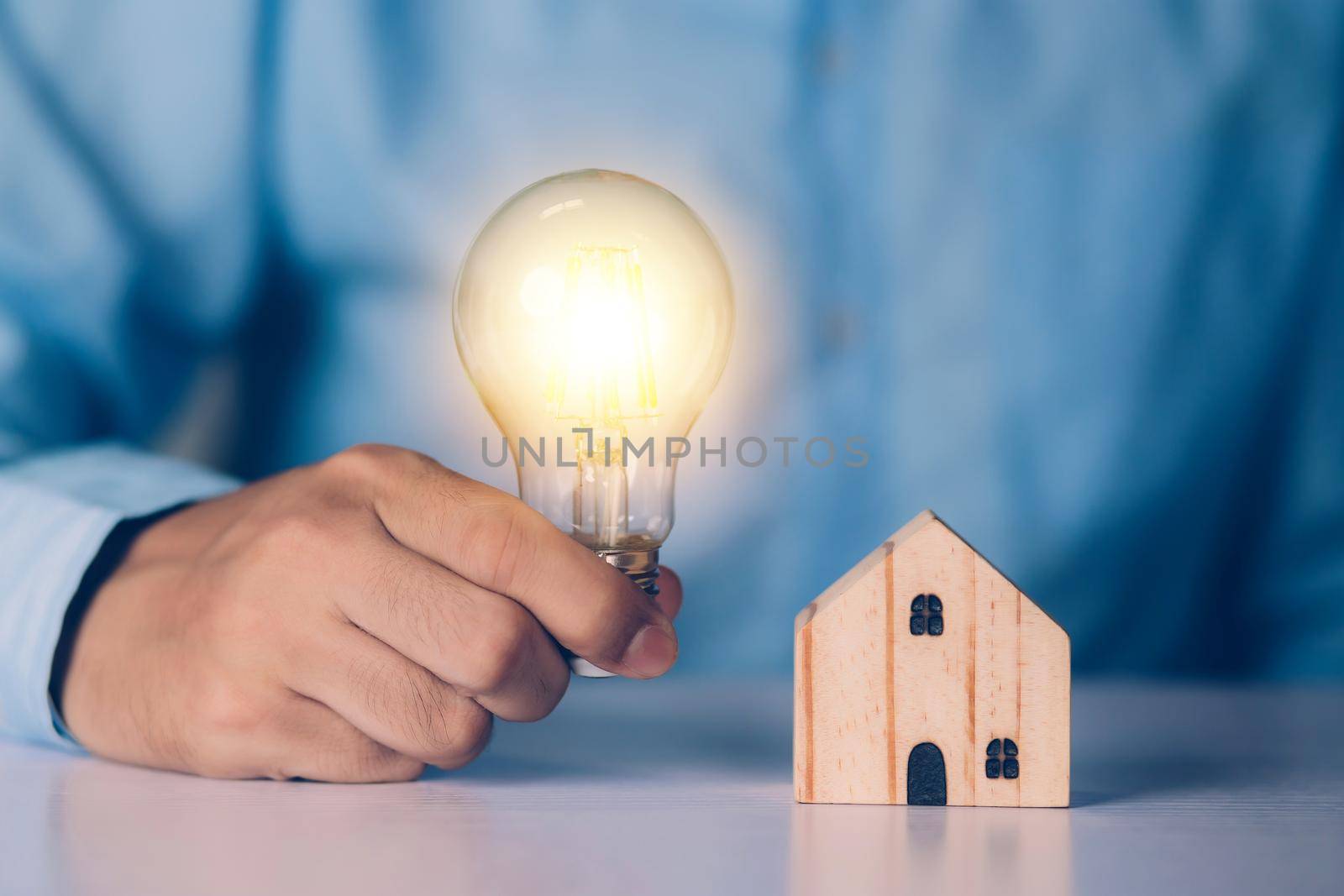 Businessman holding light bulb while home wooden for solution innovation and environment, thinking idea for planning buy house, residential with eco and saving energy, business and finance concept.