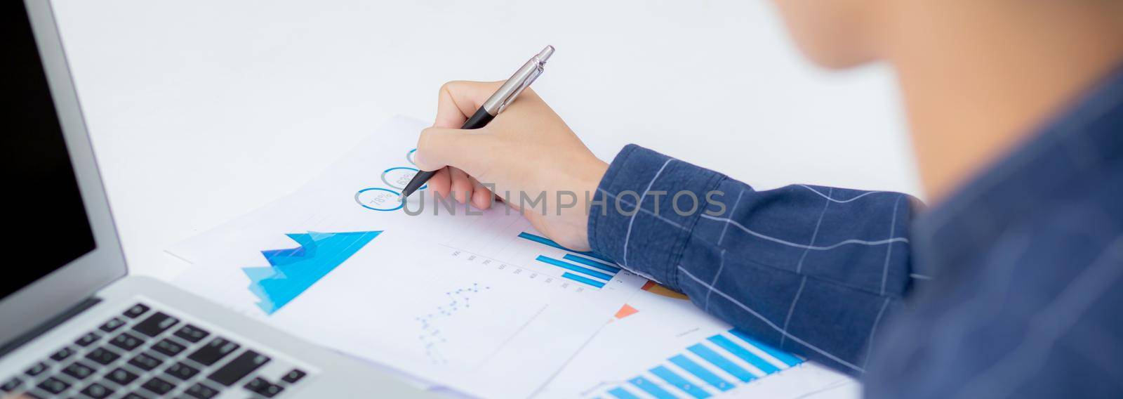 Young asian business man pointing document data graph and chart with pen, marketing and investment, report of statistics profit for financial, economic and growth of finance, management and planning. by nnudoo