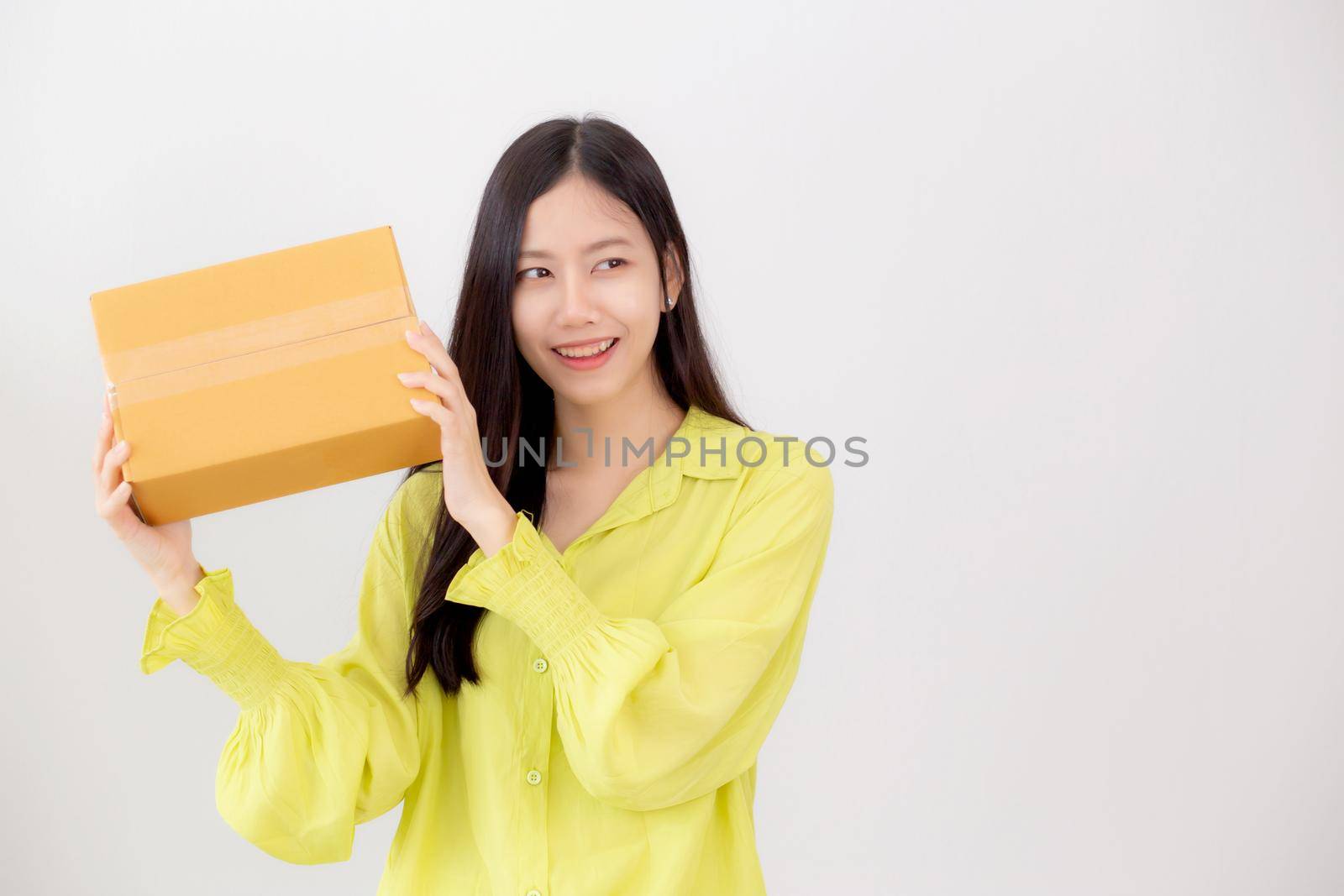 Young asian woman smiling and holding cardboard box with surprise at home, happy female carrying parcel box with excited, present and gift, packaging for deliver, online shopping store and service concept.