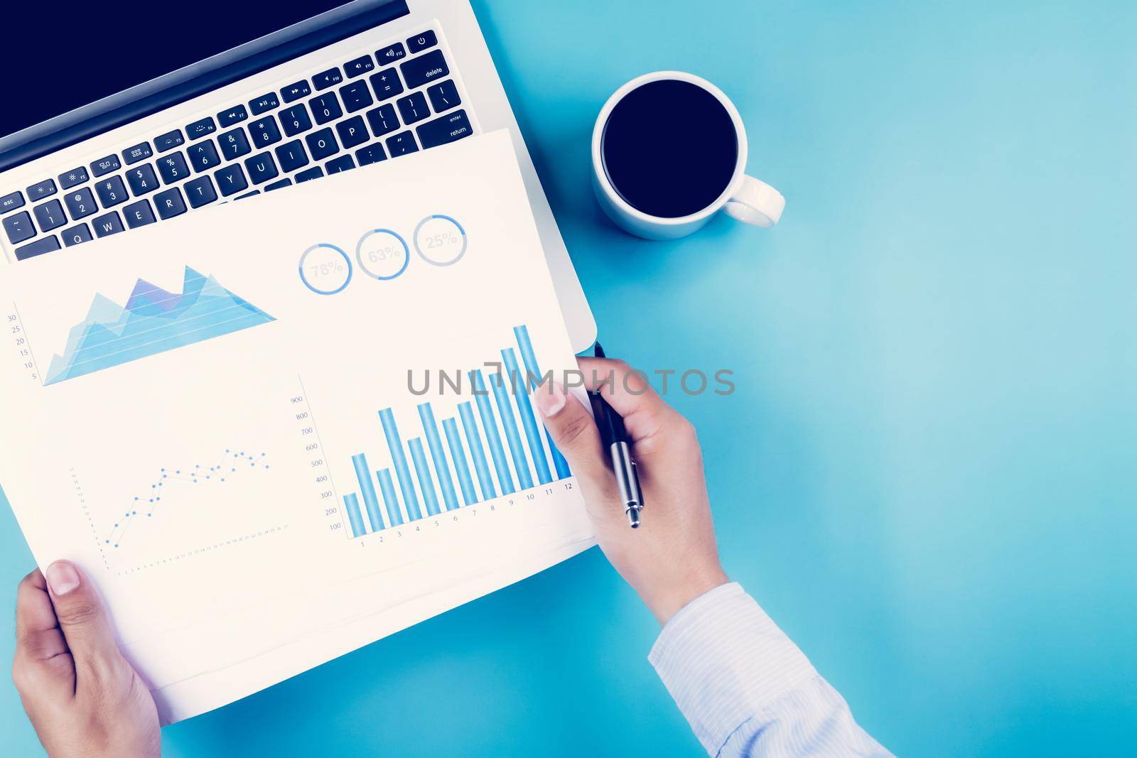 Hand of businessman holding documents report statistic financial with graph and chart and laptop computer and coffee on desk, finance and invest, digital marketing, business and communication concept.